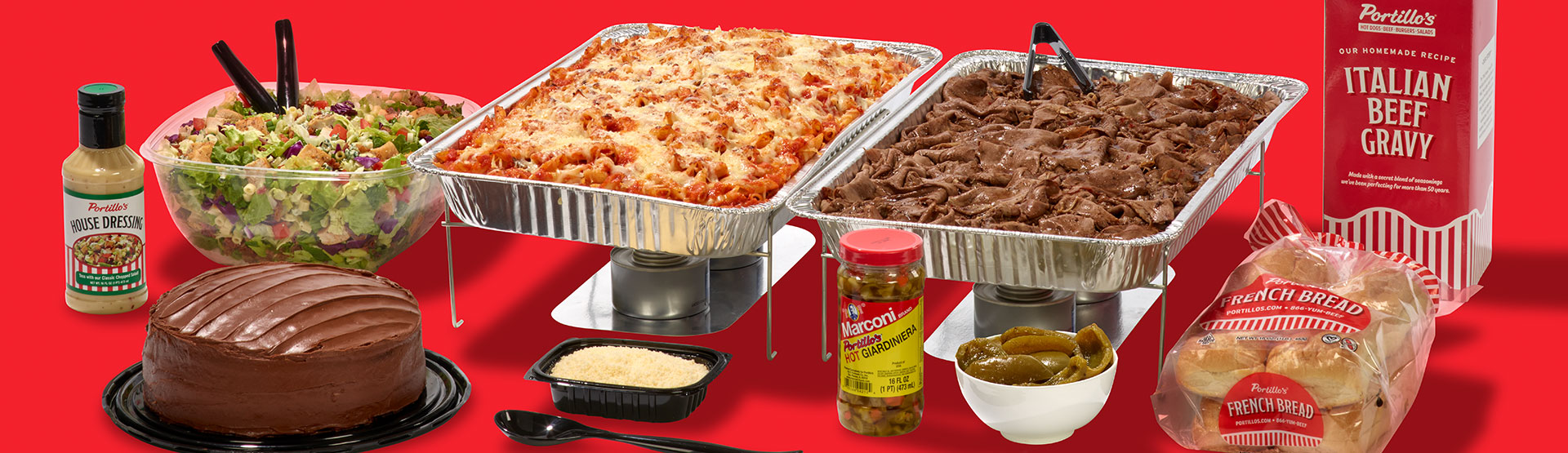 Table scape of Portillo's catering items including salad in a bowl, chocolate cake, mostaciolli, italian beef, and more