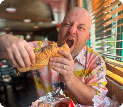 man about to bite into a beef sandwich